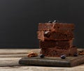 Stack of square baked slices of brownie chocolate cake with walnuts on a wooden surface. Cooked homemade food. Chocolate pastry