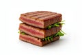 Stack of square grilled meat slices with pink center and green arugula between layers. Royalty Free Stock Photo
