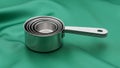 Stack of stainless steel measuring cups on a green fabric surface Royalty Free Stock Photo