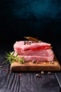 Stack of steaks of fresh raw pork meat decorated with chili peppers and rosemary on a dark background. Royalty Free Stock Photo