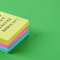 Stack of sticky notes in yellow, pink, and blue on a green background. The top note, Royalty Free Stock Photo