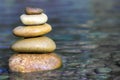 Stack of stones balancing on top in blue water of the river