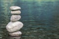 Stack of stones balancing on top in blue water of the river