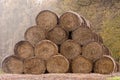 The stack of straw bales waiting to be used in a farm. Round straw bales on a field stacked in a pyramid. Trees in the background Royalty Free Stock Photo