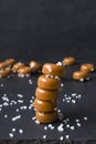 Stack of sweet caramel candy with salt on the black surface against dark background Royalty Free Stock Photo