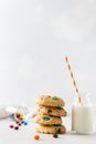 Stack of sweet cookies with colorful candies for children and a bottle of milk on white background. Side view, copy space. Bakery Royalty Free Stock Photo