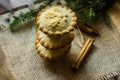 Stack of sweet mince pies on sackcloth on wood box with cinnamon sticks and fir tree branches Royalty Free Stock Photo