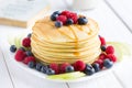 Stack of Sweet Pancakes with Fresh Blueberry, Raspberry, Apple and Maple Syrup on White Light Background