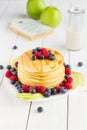 Stack of Sweet Pancakes with Fresh Blueberry, Raspberry, Apple and Maple Syrup on White Light Background