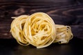 Stack of tagliatelle pasta nests over dark wooden background Royalty Free Stock Photo