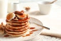 Stack of tasty pancakes with banana, nuts and syrup