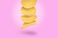 Stack of tasty potato chips falling on light violet background Royalty Free Stock Photo