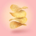 Stack of tasty potato chips falling on pink background Royalty Free Stock Photo