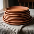 A stack of terracotta plates is neatly placed on a folded beige linen cloth. These Royalty Free Stock Photo