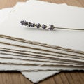 Stack of textured, cream-colored handmade paper on a wooden surface, with a sprig o Royalty Free Stock Photo