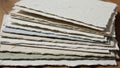 A stack of textured handmade paper sheets is arranged on a wooden surface Royalty Free Stock Photo
