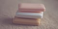 Stack of three bars of soap different colors on a brown towel.