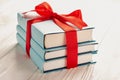 A stack of three books tied with a red ribbon with a bow: the concept of a good book - a good gift