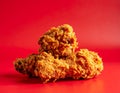 Stack of three golden brown fried chicken pieces on a red background food crispy Royalty Free Stock Photo