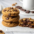 A stack of three gooey chocolate chip cookies with walnuts, one split in half revealing melted chocolate, on white parchment paper Royalty Free Stock Photo