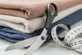 Stack of three knitted fabrics, scissors of dressmaker and measuring tape on tabletop Royalty Free Stock Photo