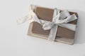 Stack of three old, vintage books tied up with beige ribbon with linen hard cover. Silk bow. White table background