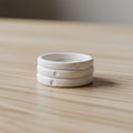 A stack of three white ceramic rings rests on a light wooden surface. Each ring Royalty Free Stock Photo