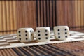 Stack of three white plastic dices on brown wooden board background. Six sides cube with black dots. Number 6