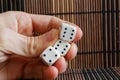 Stack of three white plastic dices in man`s hand on brown wooden table background. Six sides cube with black dots. Number 4, 6, 6 Royalty Free Stock Photo