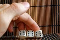 Stack of three white plastic dices in man`s hand on brown wooden table background. Six sides cube with black dots. Number 6, 6, 6 Royalty Free Stock Photo