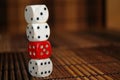 Stack of three white plastic dices and one red dice on brown wooden board background. Six sides cube with black dots. Number 3, 4, Royalty Free Stock Photo