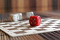 Stack of three white plastic dices and one red dice on brown wooden board background. Six sides cube with black dots. Number 5 Royalty Free Stock Photo