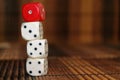 Stack of three white plastic dices and one red dice on brown wooden board background. Six sides cube with black dots. Number 1, 3, Royalty Free Stock Photo