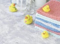 Stack of towels with yellow rubber bath ducks on white marble background, space for text, selective focus Royalty Free Stock Photo