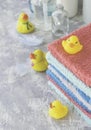 Stack of towels with yellow rubber bath ducks on white marble background, space for text, selective focus Royalty Free Stock Photo