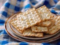 Crispy matzo crackers stacked on ceramic plate over blue checkered fabric background Royalty Free Stock Photo