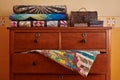 Stack of traditional quilts and wooden chest on chest of drawers Royalty Free Stock Photo