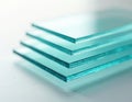 Stack of transparent glass sheets with clear edges and subtle blue tint. Material arranged neatly on clean white surface, Royalty Free Stock Photo