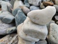 Stack of triangular stones.Group of white and colorful Stones.Pebble tower on the stones seaside.Stones pyramid on pebble beach