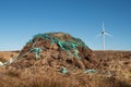 Stack of turf in a bog next to wind farm turbine. Clean new and dirty old source of energy. Natural and artificial product in Royalty Free Stock Photo