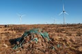 Stack of turf in a bog next to wind farm turbine. Clean new and dirty old source of energy. Natural and artificial product in Royalty Free Stock Photo