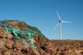 Stack of turf in a bog next to wind farm turbine. Clean new and dirty old source of energy. Natural and artificial product in Royalty Free Stock Photo