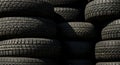 A stack of used black tires arranged in multiple rows. The tires display various