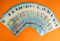 A stack of used blue 20 euro banknotes isolated on a vivid orange background.
