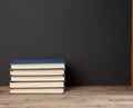 Stack of various hardback books on the background of an empty black chalk board Royalty Free Stock Photo