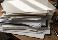 A stack of various types of paper lies on a wooden desk. The papers vary in texture, Royalty Free Stock Photo