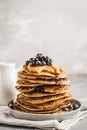 Stack vegan blueberry pancakes with peanut butter and syrup.