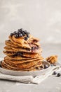 Stack vegan blueberry pancakes with peanut butter and syrup.