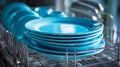 Stack of vibrant blue ceramic plates neatly arranged on a metal rack inside a dishwasher ready for cleaning or drying in a modern Royalty Free Stock Photo