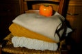 Stack of warm knitted sweaters in sunlight on wooden chairs across wooden dresser close-up and orange persimmon on the top. Warm c Royalty Free Stock Photo